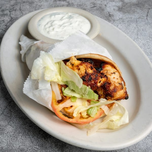 Opa Grille's chicken souvlaki pita wrap with lettuce, tomato, and a side of tzatziki sauce.