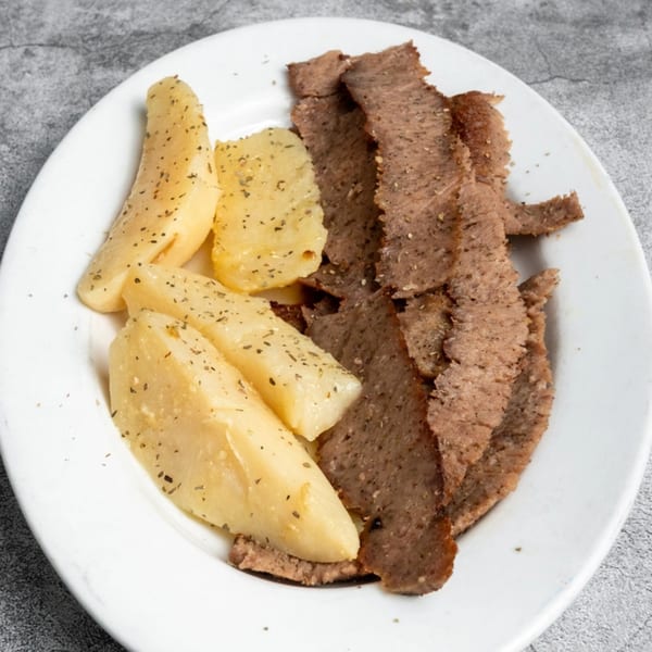 Opa Grille's Greek gyro meat and seasoned potato wedges on a white plate.