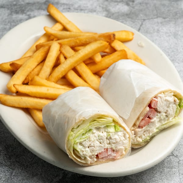 Two chicken salad wraps with lettuce and tomato, served with a side of golden french fries.