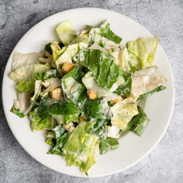 Opa Grille's Caesar salad, featuring crisp romaine lettuce, creamy dressing, and crunchy croutons.