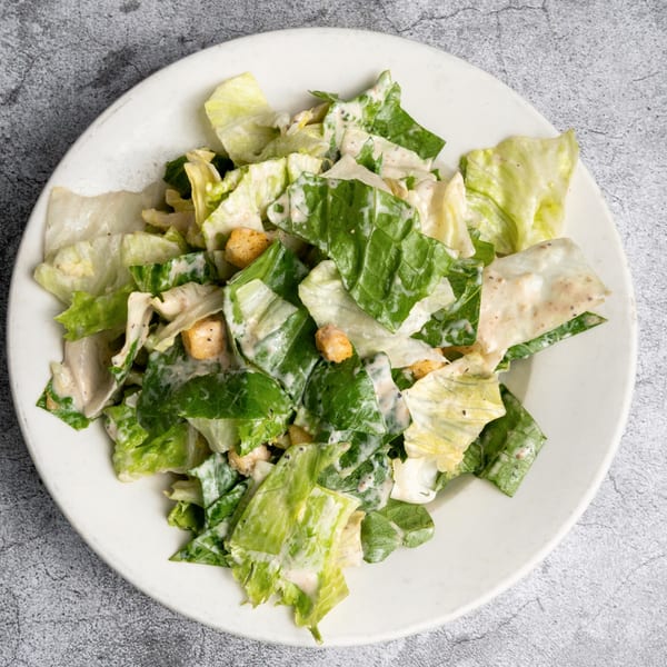 A white plate filled with crisp green lettuce, creamy dressing, and golden croutons.