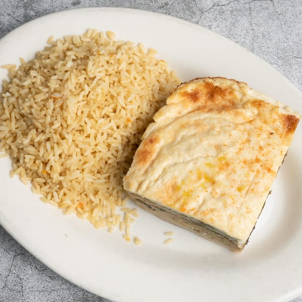 A serving of Opa Grille's pastitsio, a Greek baked pasta dish, with a side of rice.